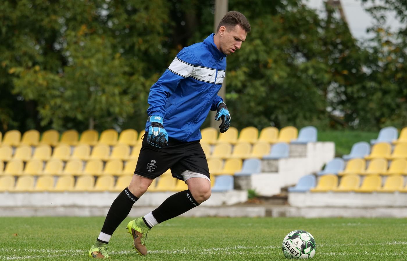 Goleiro treina com a bola em um campo de futebol
